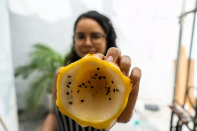 Una adolescente muestra en primer plano la mitad de una fruta