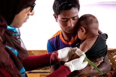 Un enfant dans les bras de son père se fait soigner contre la malnutrition