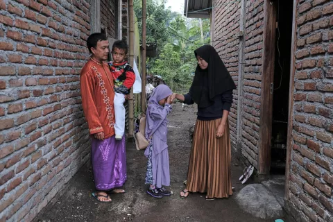 نازريادي ورقية تستعدان لاصطحاب أطفالهما إلى المدرسة أمام منزلهما في قرية جينينج، شرق لومبوك، إندونيسيا، في 4 ديسمبر 2020. تتلقى نازريادي ورقية المساعدة النقدية من اليونيسف لدفع ثمن تكاليف تعليم أطفالهما.