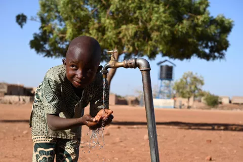 Un garçon boit de l'eau grâce à un système d'alimentation en eau fonctionnant à l'énergie solaire.