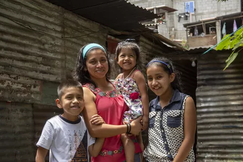 Guatemala. A woman stands with her family.