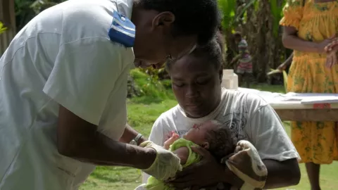Une infirmière administre un vaccin à un bébé de 1 mois tenu par sa mère, Vanuatu. 