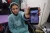 A girl seated in a wheelchair holds her mobile phone to show a picture of herself before her injury.