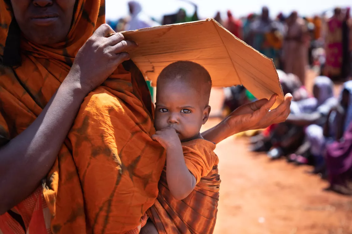 在埃塞俄比亚索马里地区的黑加勒，一位母亲用一块纸板保护儿子不被阳光晒伤。