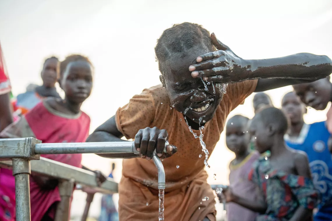 在南苏丹团结州的一个境内流离失所者营地，一名女孩在联合国儿童基金会支持安装的水龙头旁洗脸。