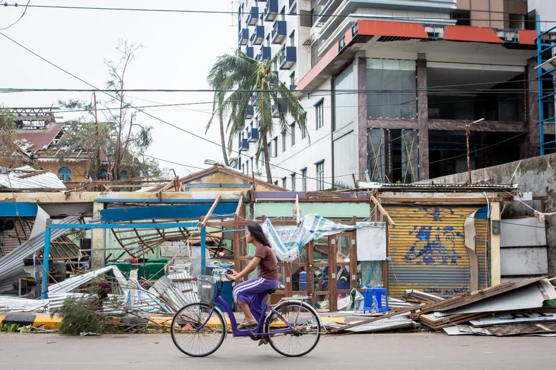 امرأة على دراجة قرب مبانٍ تضررت بشدة نتيجة إعصار موكا في ولاية راخين، ميانمار، في 14 أيار/مايو 2023.