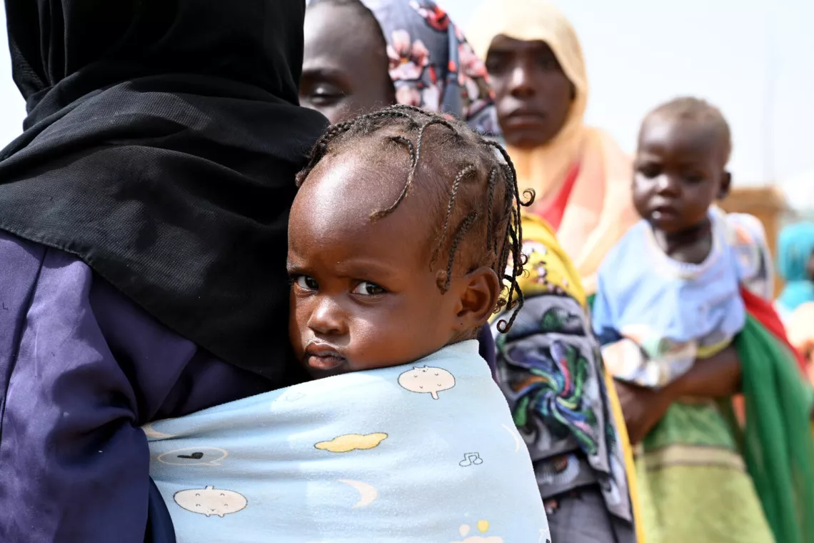 أم تحمل طفلها على ظهرها في مركز للاجئين شرقي تشاد، قرب الحدود مع السودان.