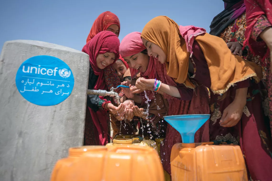 在阿富汗巴尔赫省，一群女孩使用联合国儿童基金会援助安装的水龙头喝水。