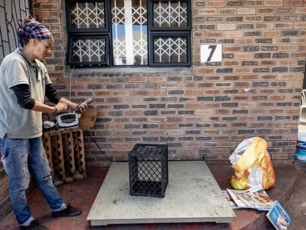 A woman looks at an app on her phone where she records the weight of the waste dropped off.