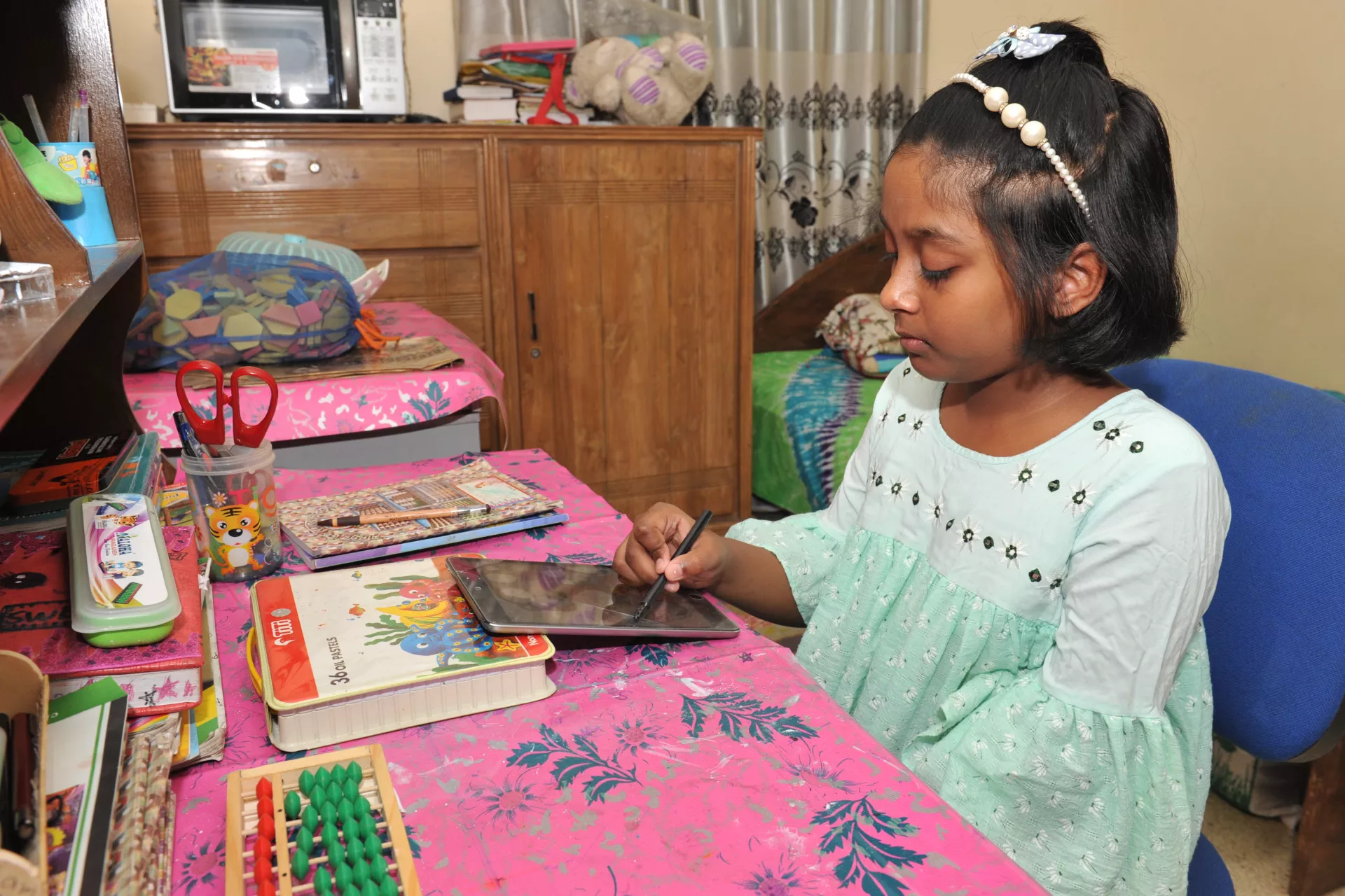 Mounee Mahdeya, 10, uses her computer tablet to complete schoolwork