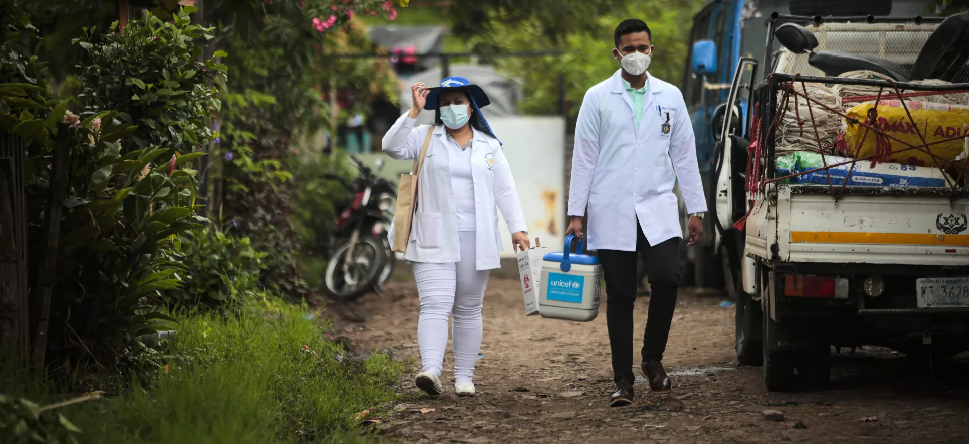 Deux agents de santé vêtus de blouses blanches marchent dans une rue. 