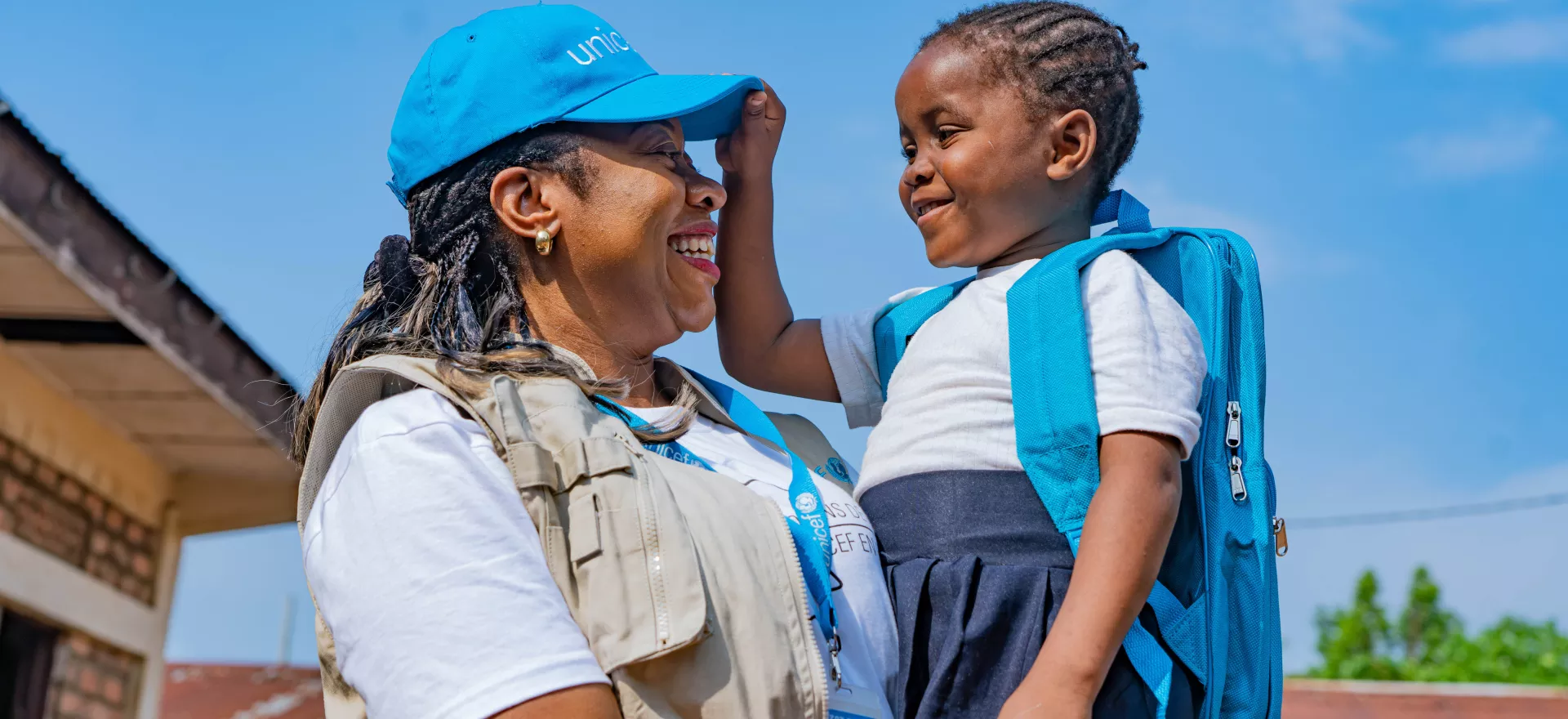 A UNICEF colleague holding a young child who just received a school kit