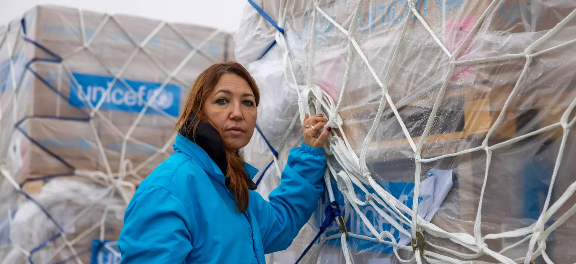 Une membre du personnel de l’UNICEF se tient devant des cargaisons de fournitures essentielles 