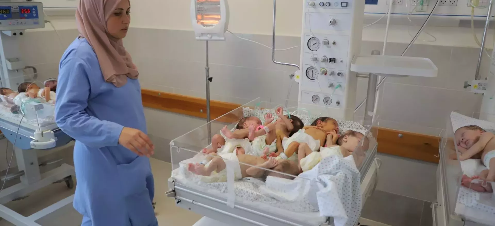 Des bébés dans des couveuses dans un hôpital. Une femme médecin est debout près d’eux. 