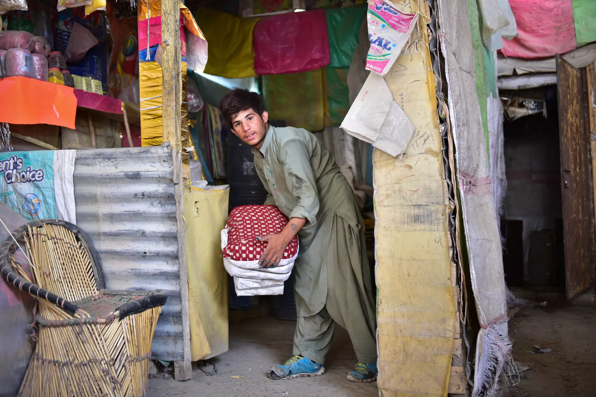 A boy lifts a crate at a market, Pakistan