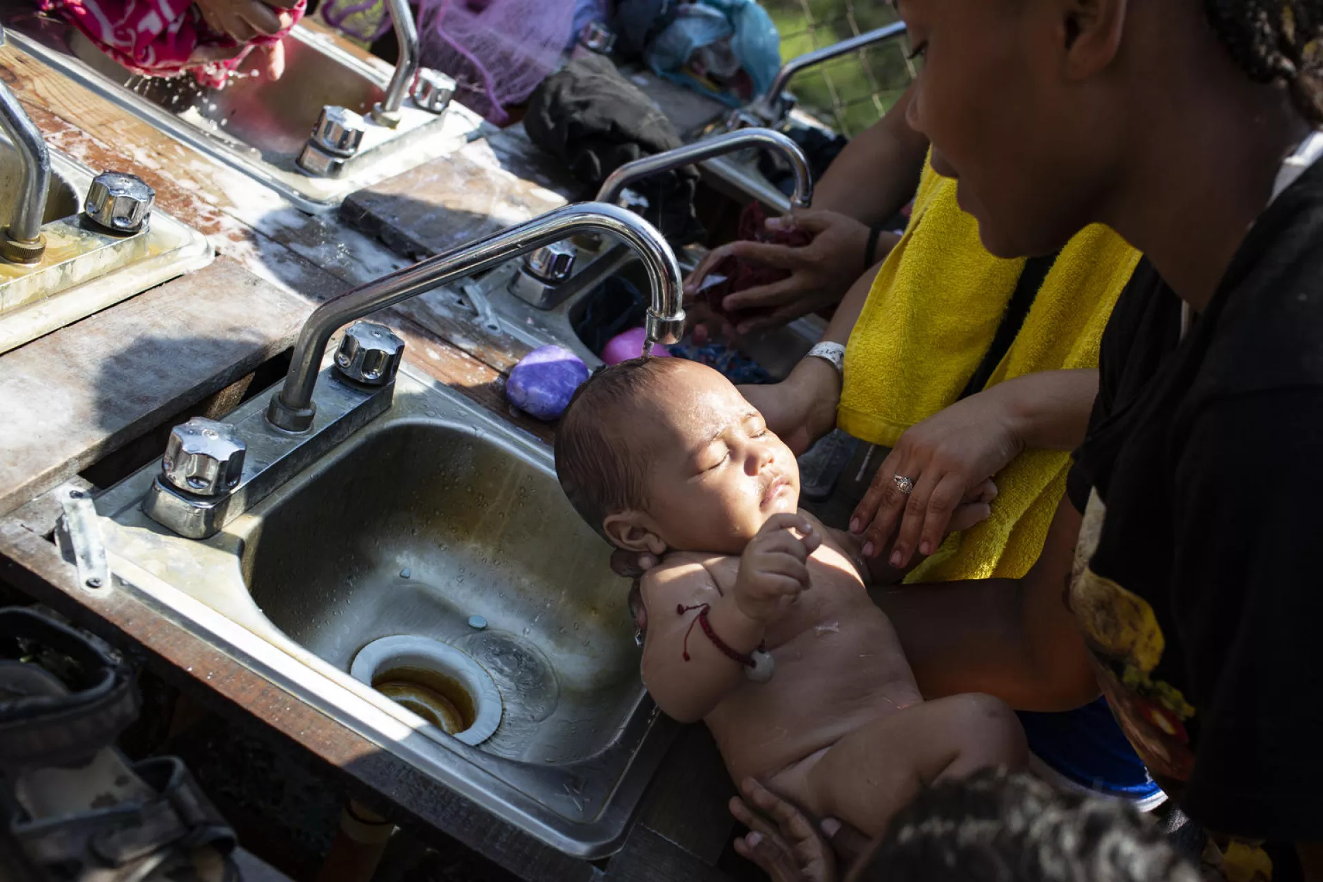 Una madre migrante baña a su bebé