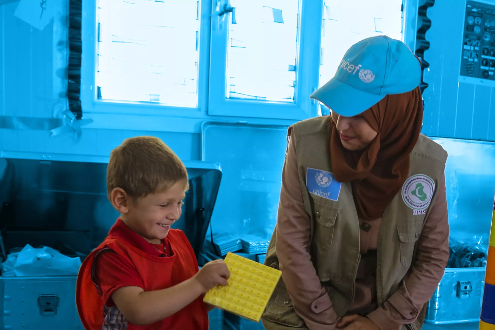 在伊拉克，一名联合国儿童基金会工作人员与一个小男孩并肩而坐