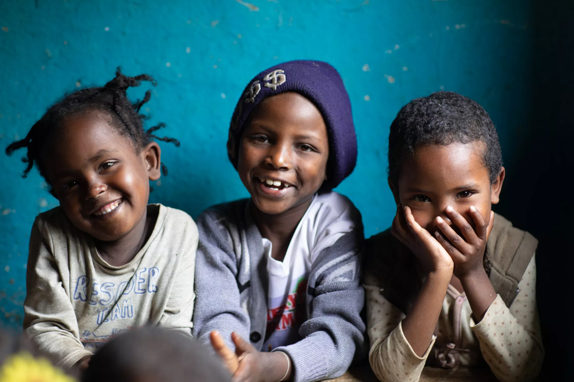 Three smiling young children in Ethiopia.