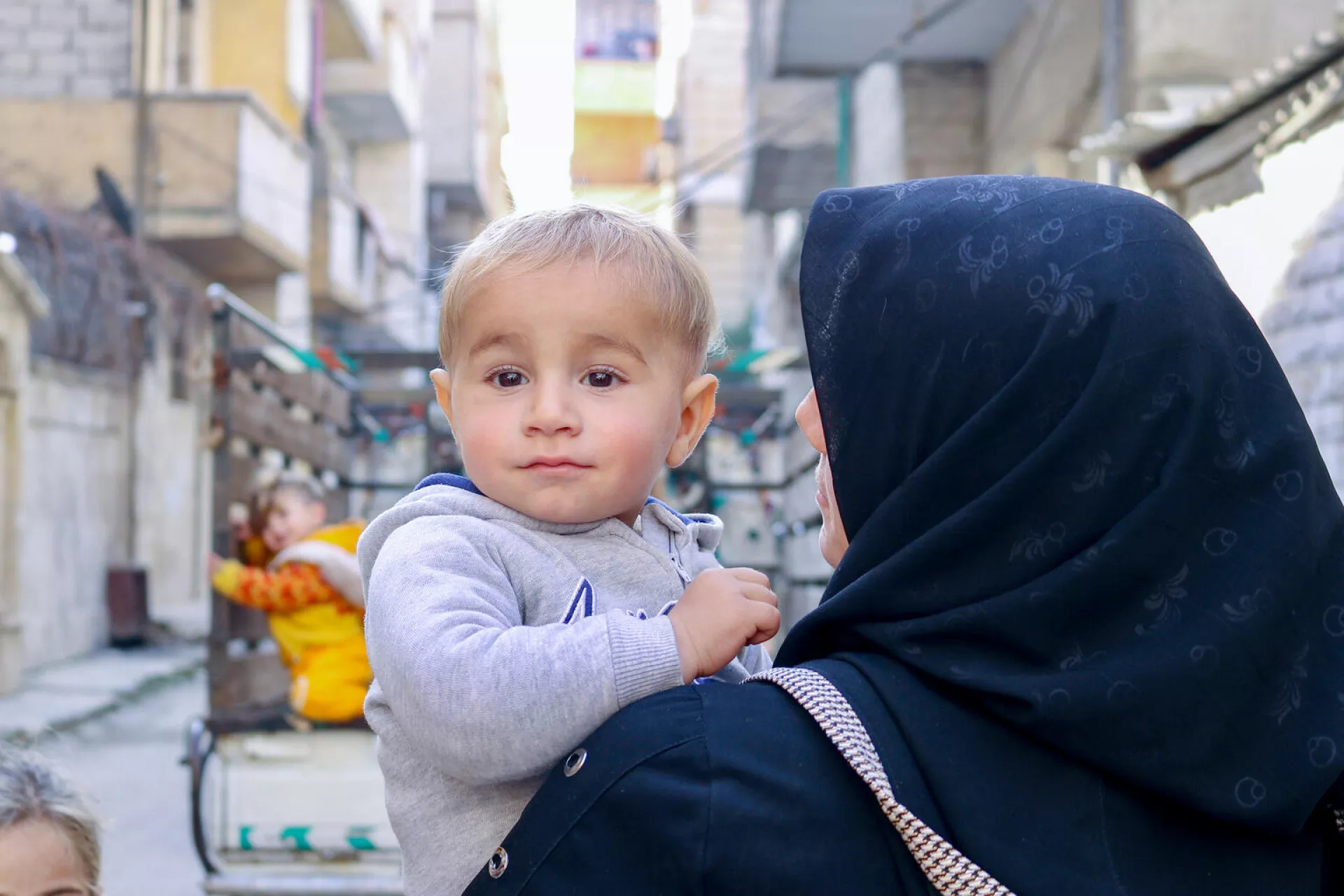 Syria. A mother holds her child outside a UNICEF-supported health and nutrition centre in Aleppo.