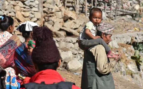 A grandfather in Nepal carrying his grandson on his shoulders