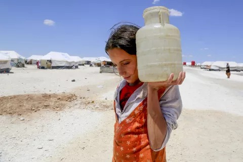 在叙利亚，一个女孩肩上扛着一个水桶