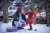 Un enfant met des chaussures neuves avec l’aide d’un agent de l’UNICEF. Dans un paysage enneigé. 