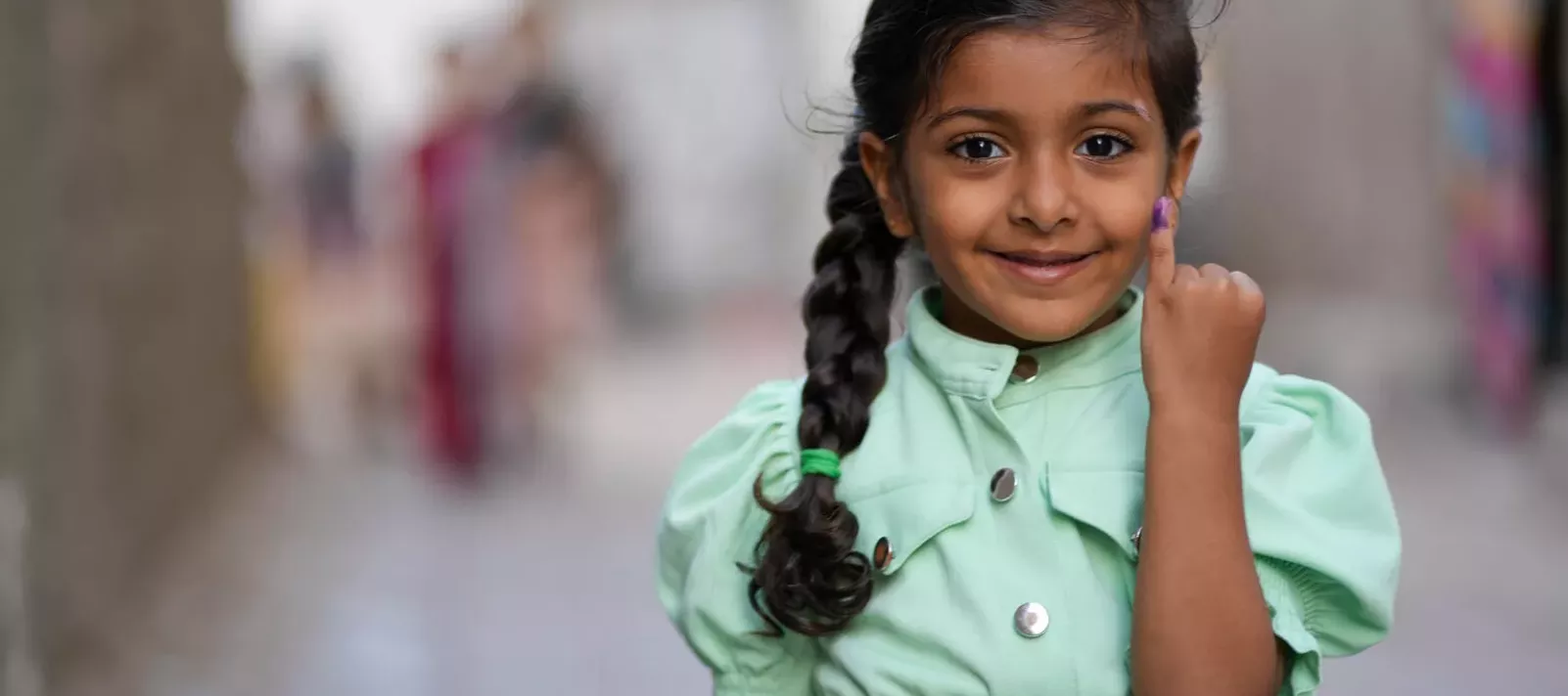 فتاة صغيرة فخورة تعرض إصبعها الملوّن بعد تلقيها اللقاح المضاد لشلل الأطفال في اليمن.