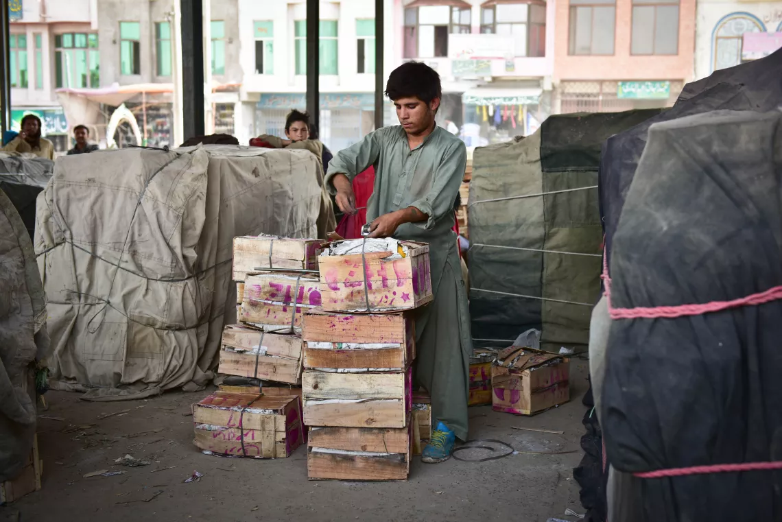 A boy puts a metal strip on a carton, Pakistan