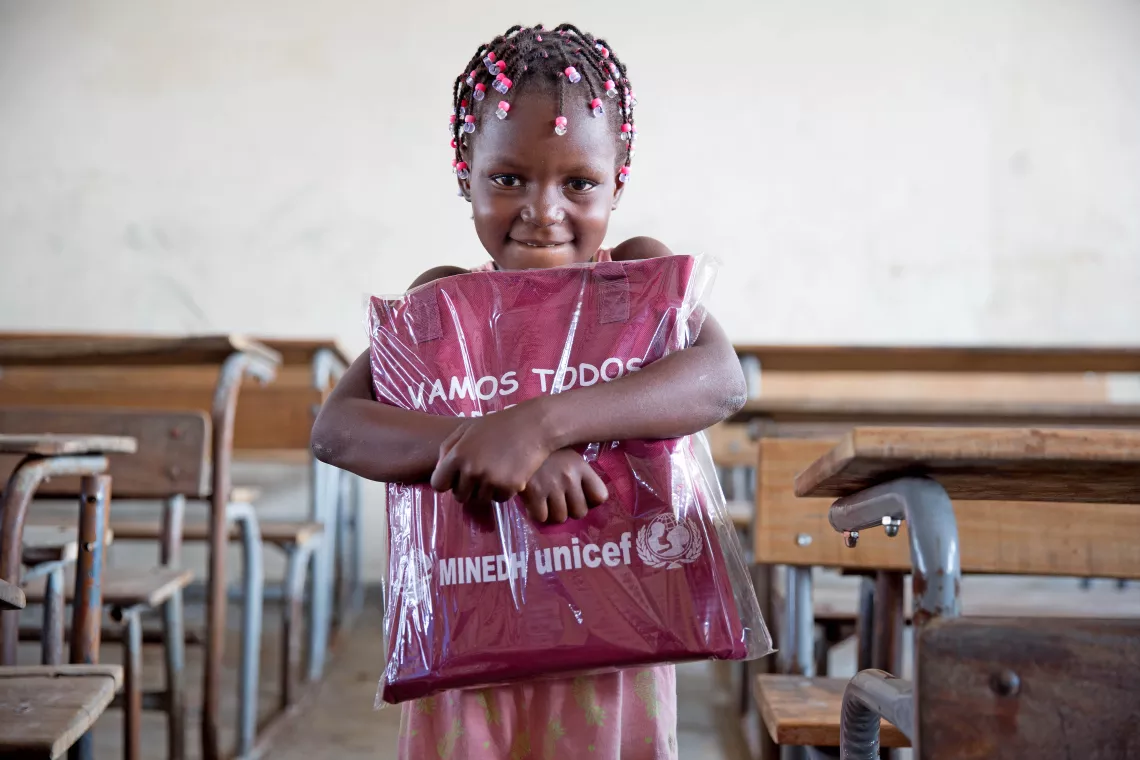 Mozambique. A child holds an education pack.