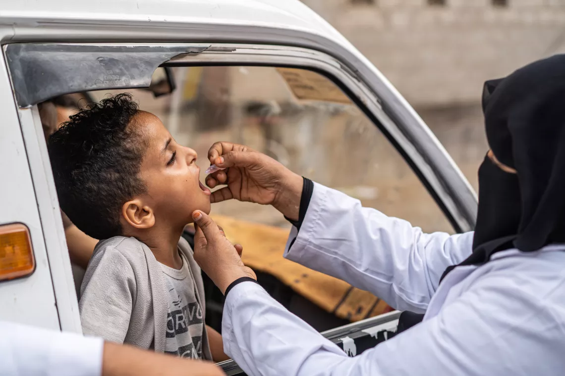 A health worker vaccinates 5-year-old who sits inside a van, during an immunization campaign against polio.