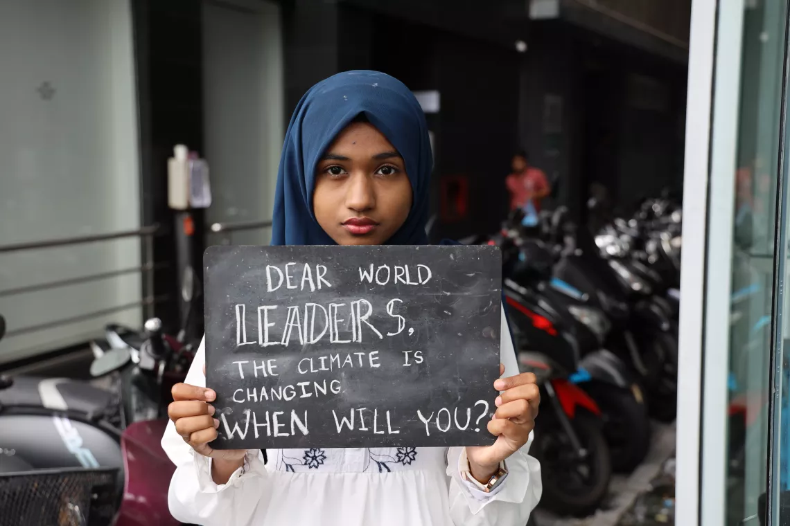 A girl holding a sign to global leaders