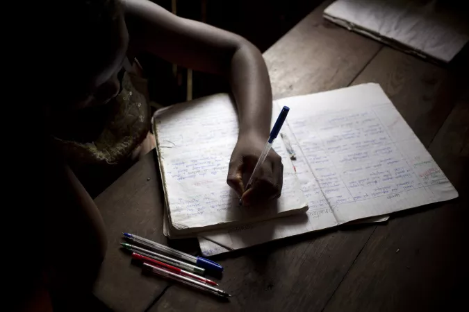 Young girl does her homework inside her family home in Madagascar