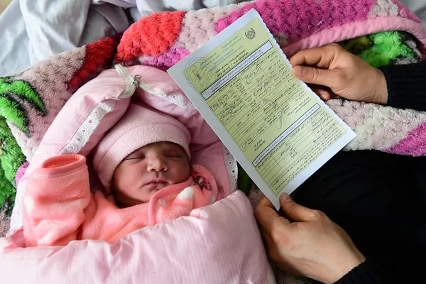 Una madre recibe un certificado de nacimiento de su bebé recién nacido en Kabul, Afganistán.