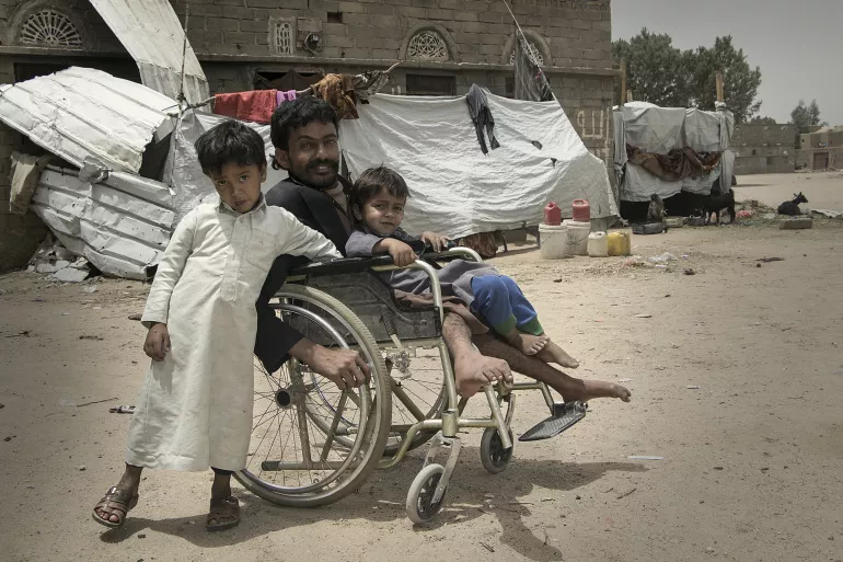 رجل في كرسي متحرك مع ولدين، اليمن