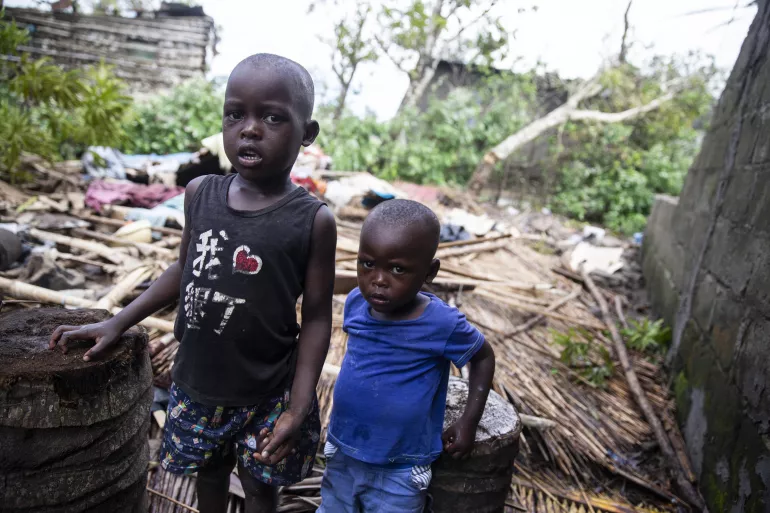 Mozambique. Two brothers stand next to the rubble that used to be there house.
