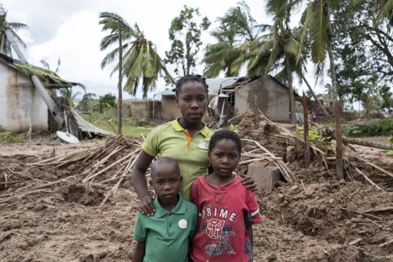 Mozambique. A family stands by a destroyed house.